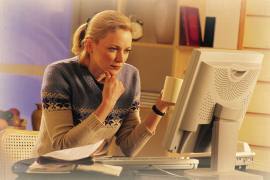 Woman looking at computer and holding coffee cup